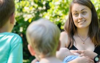 Baby stillen beim zweiten Kind - Mama mit stillendem Baby und zwei Jungen